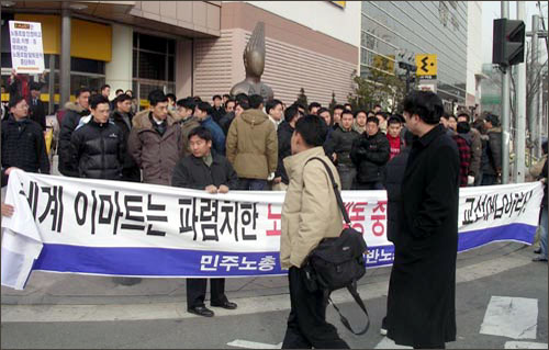 경기일반노조 조합원들이 용역경비들에 의해 도로 경계석까지 떠밀려 나와 펼침막을 펼치고 있다. 